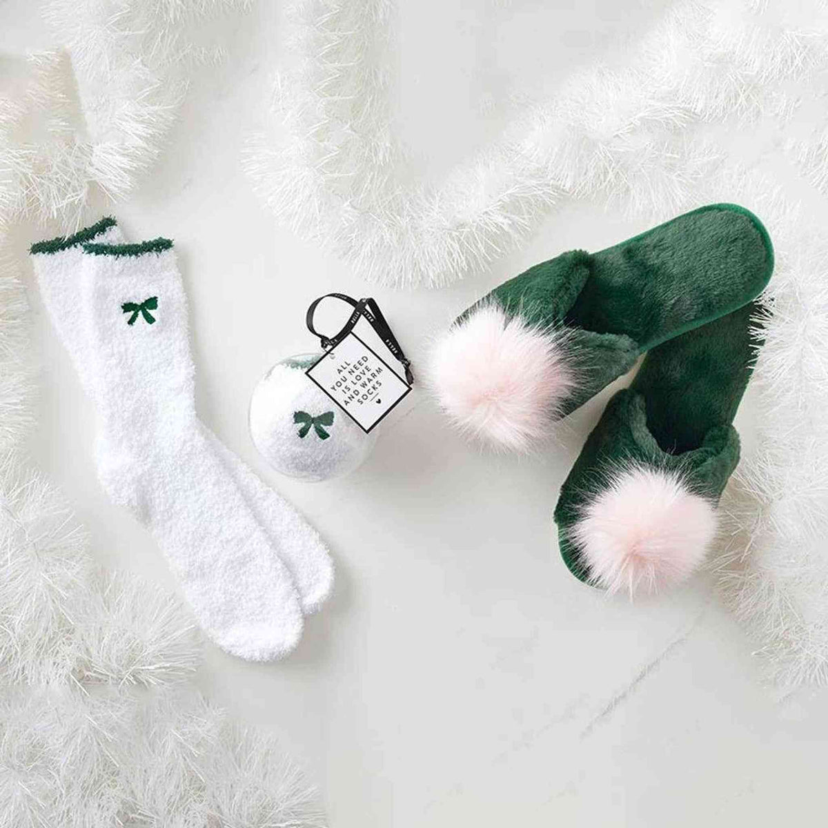 
                  
                    White cozy socks with green bow ornament and plush green slippers with pink pom-poms
                  
                