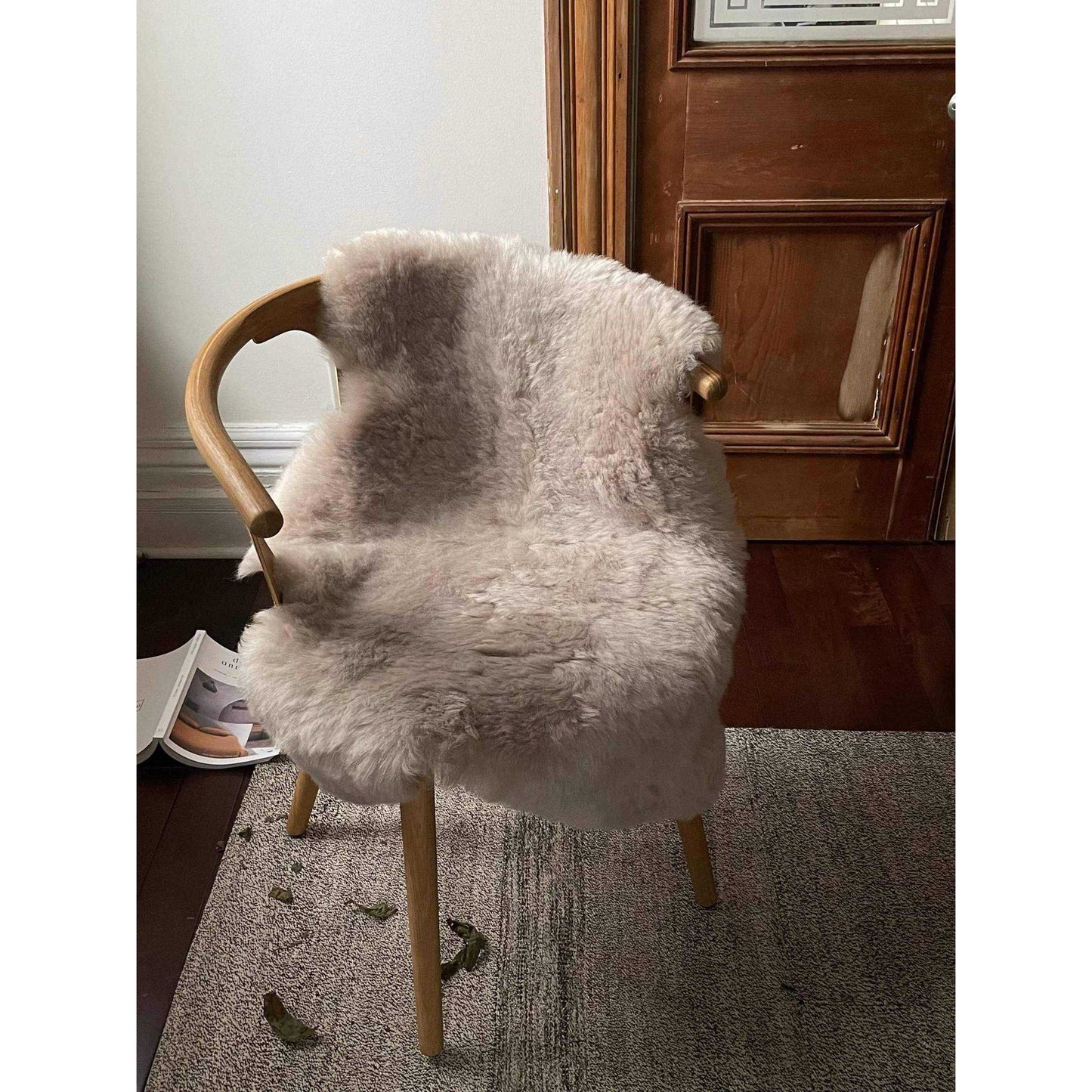 Shorn nude Icelandic sheepskin throw draped over wooden chair in cozy room