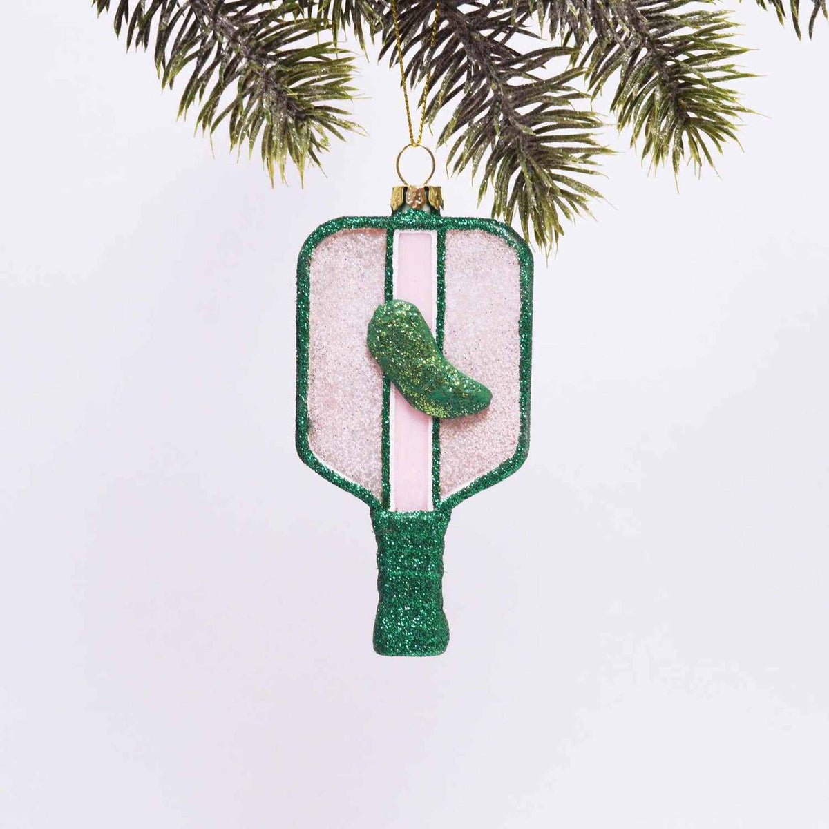 
                  
                    Pickleball boxed glass ornament hand-painted with green and pink glitter hanging on tree branch
                  
                