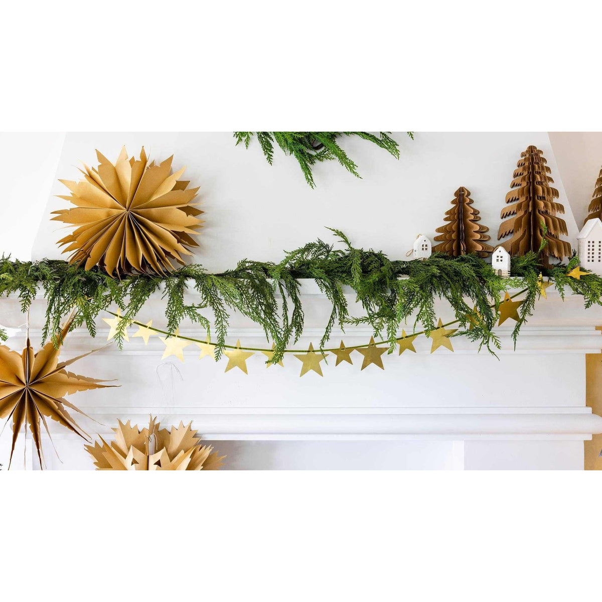 
                  
                    Christmas Memories medium 11-inch kraft paper accordion tree decor on mantel with festive greenery and gold star garland
                  
                