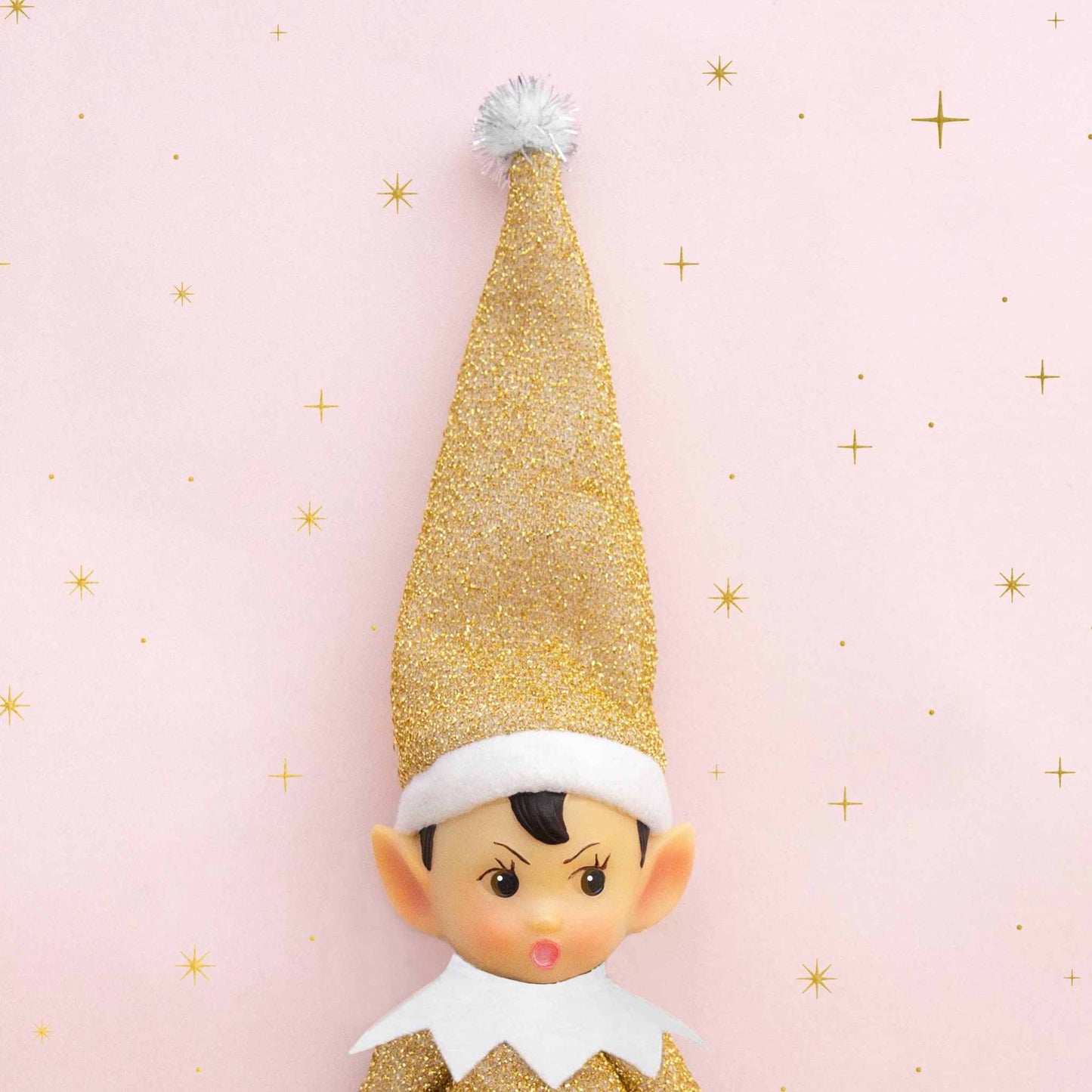 Elf Ornament Tinsel Todd with gold glitter hat and white pompom on pink star background