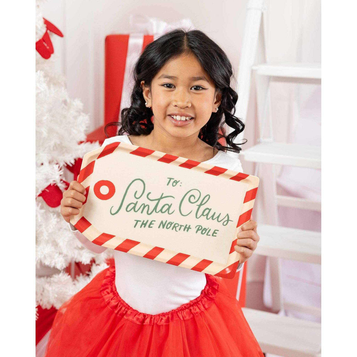 
                  
                    Child holding To Santa Tag bamboo holiday serving tray with candy cane border and festive lettering
                  
                