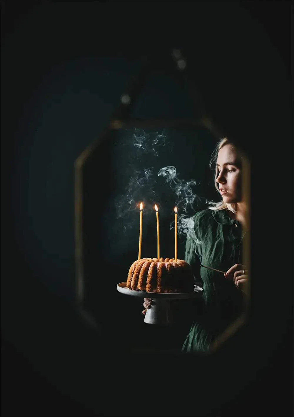 woman holding cake with lit candles in dark winter setting Nordic Winter Cookbook