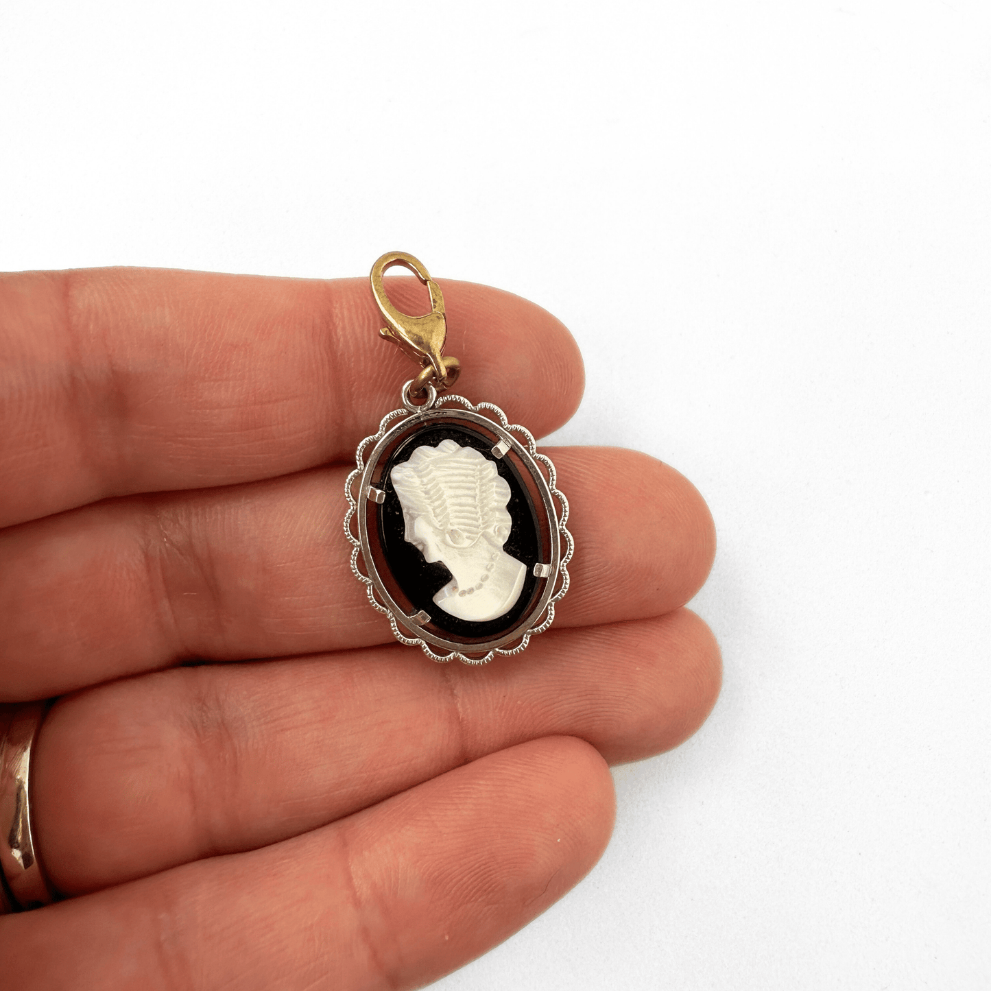 Vintage black and white cameo charm with silver setting and brass clasp on black oval base