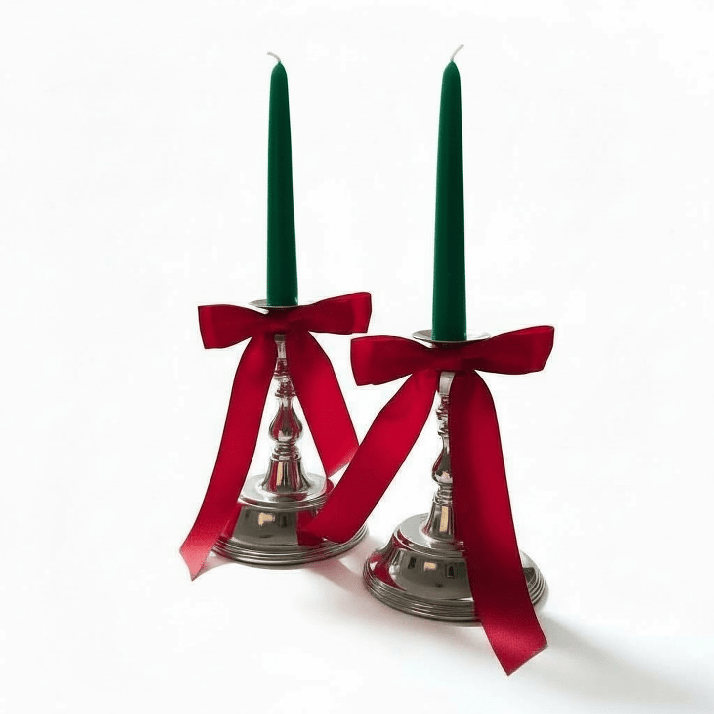 
                  
                    Pair of vintage silver plated candlesticks with red satin bows on a holiday mantel display
                  
                