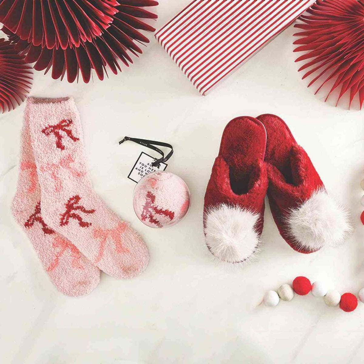 
                  
                    Cozy blush pink socks with bows and holiday-themed slippers on white background
                  
                