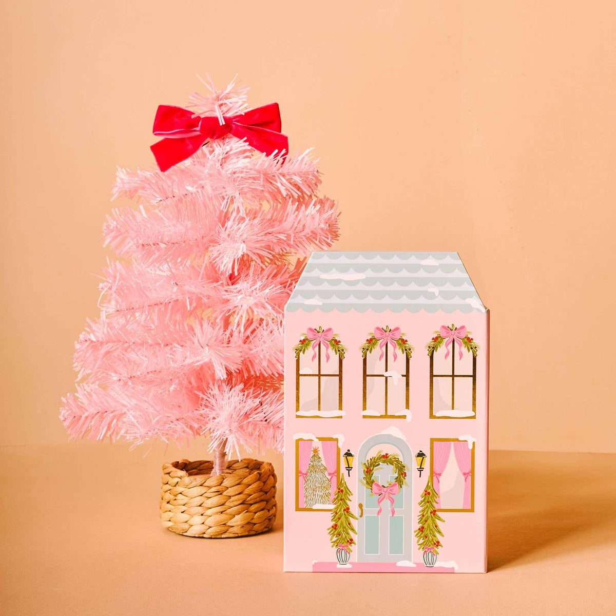 
                  
                    Pink mini artificial Christmas tree with woven basket base and red bow beside pink house-shaped advent calendar with holiday decorations and wreaths Advent Calendar & Mini Tree Bundle
                  
                