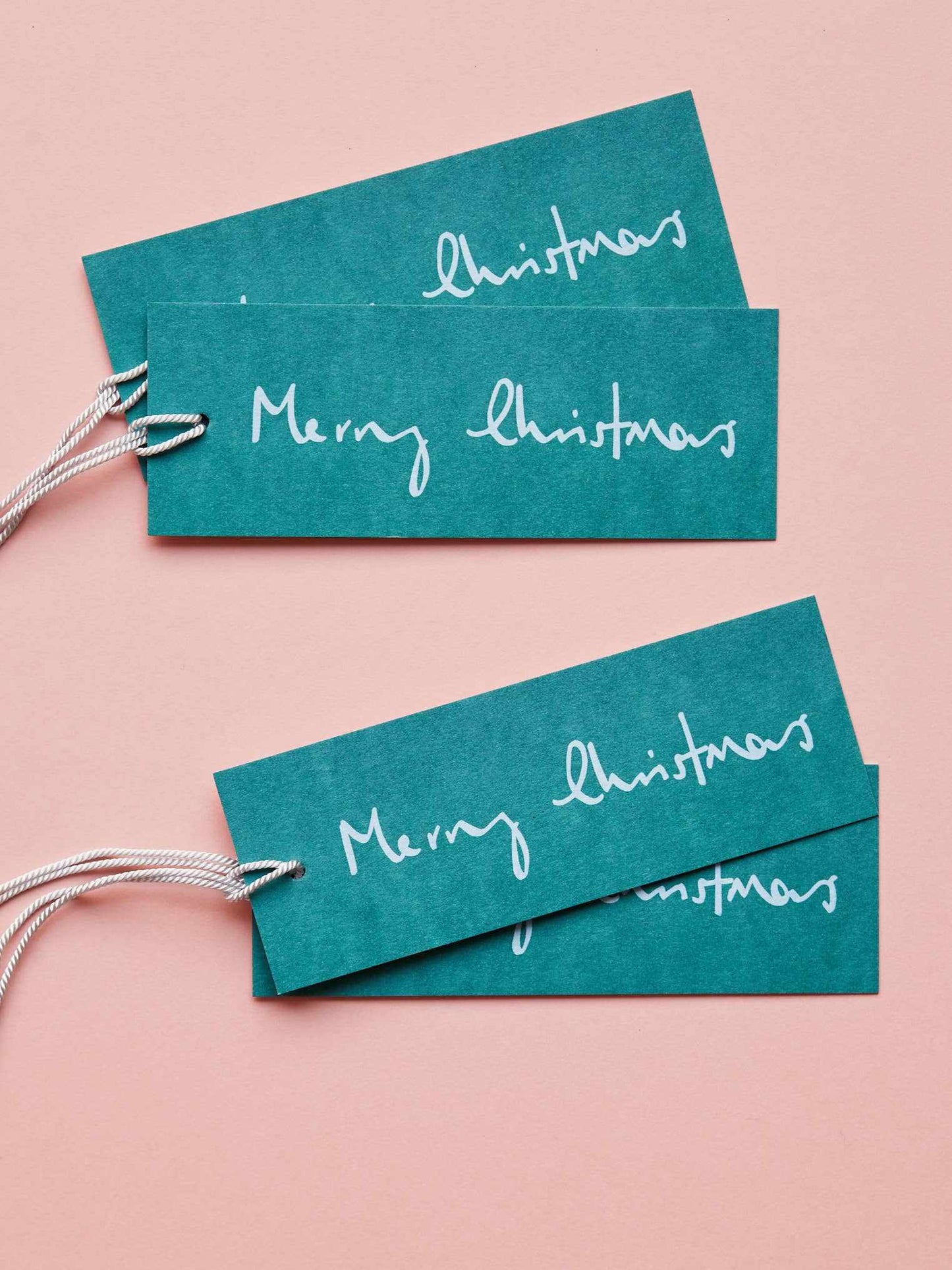 Set of 8 teal Merry Christmas gift tags on FSC-certified card with white script text and strings for tying to presents