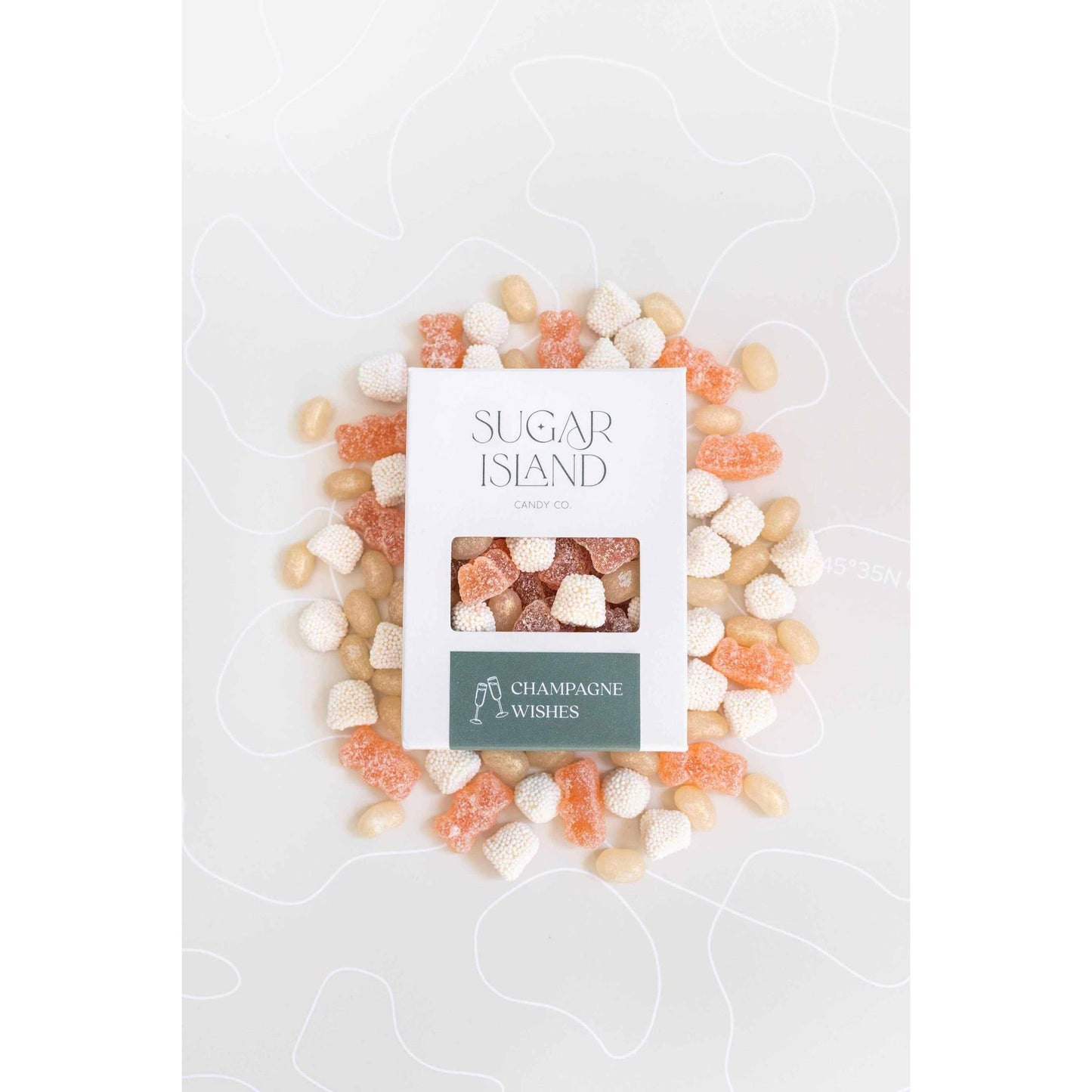 Box of Champagne Wishes Candy Mix with prosecco gummy bears, champagne bubbles, and shimmer jellybeans arranged around it