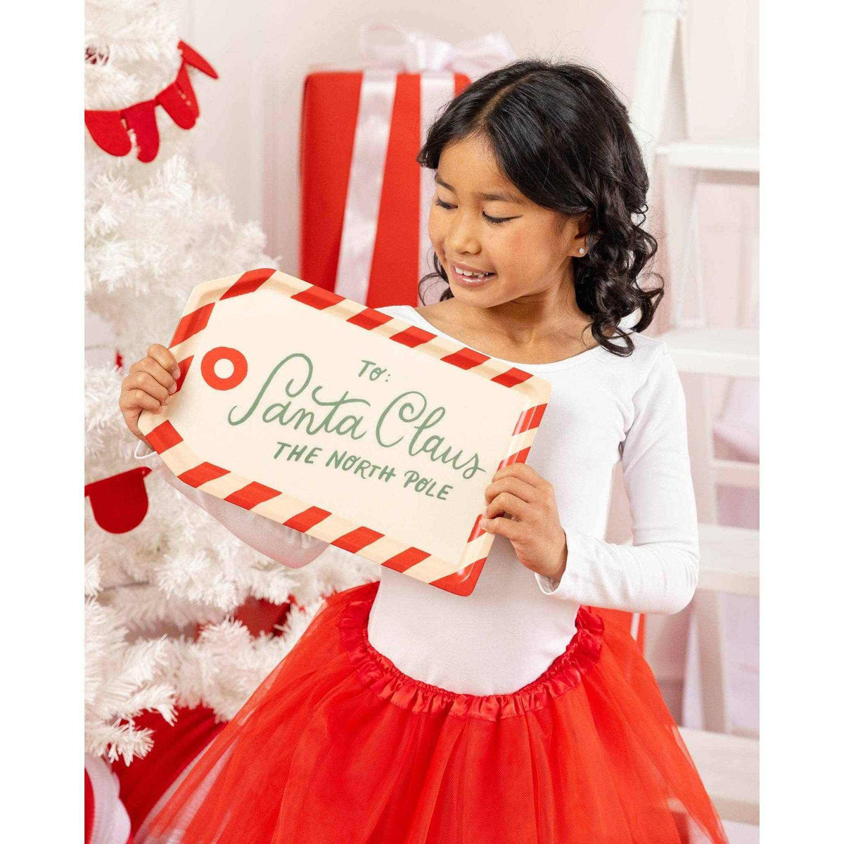 
                  
                    child holding To Santa Tag bamboo tray with holiday design near Christmas tree
                  
                