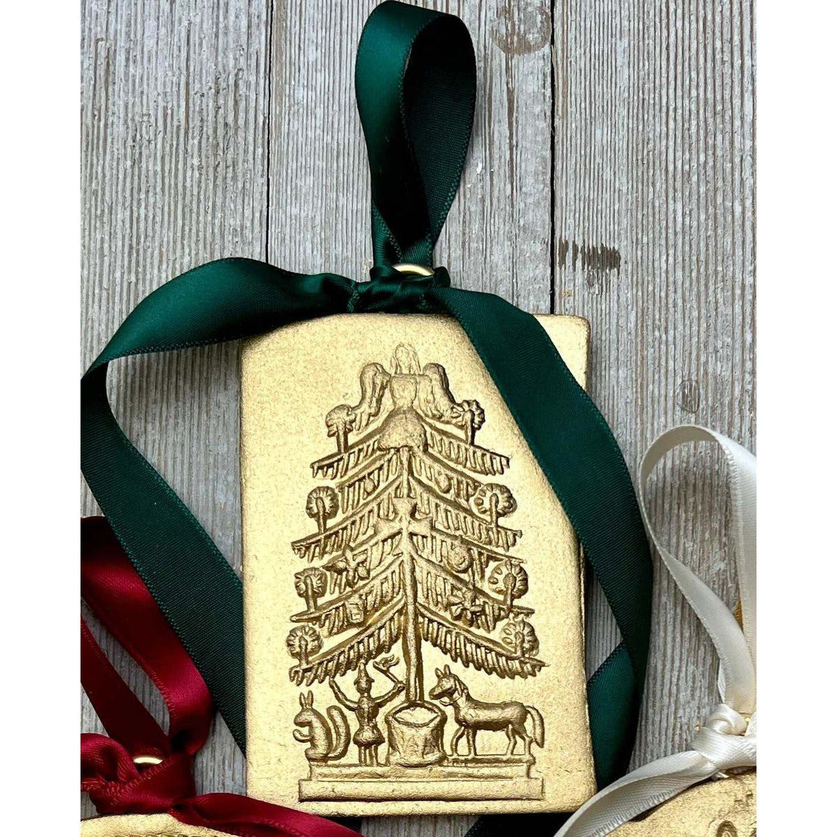 Gold Christmas ornament tree with green satin ribbon hanging on wooden background Christmas ornaments