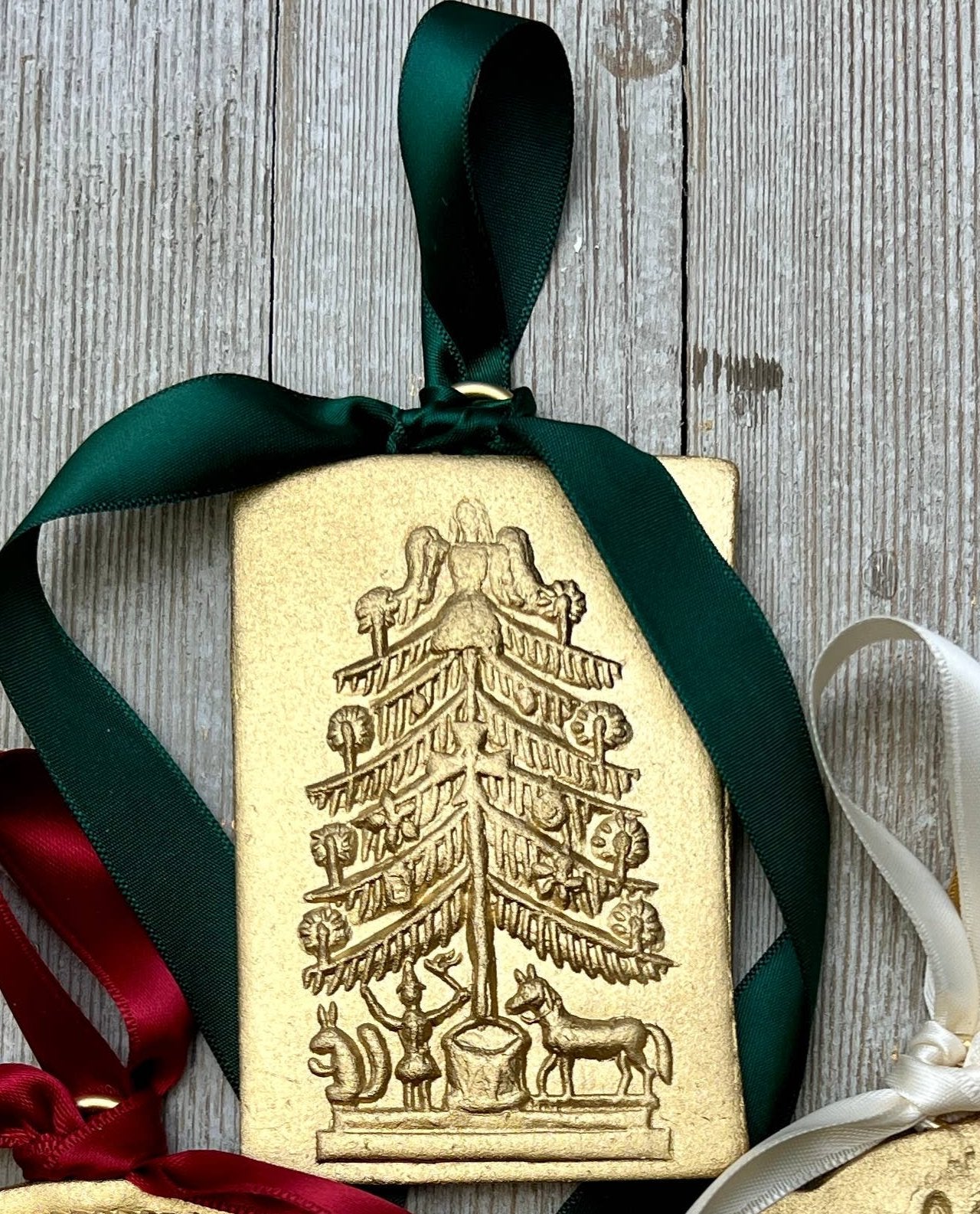 Gold clay Christmas ornament with embossed tree and green satin ribbon hanging