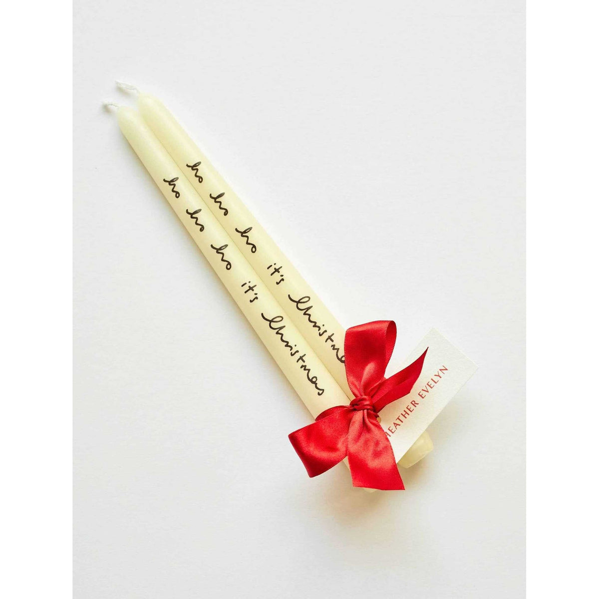 Set of 2 cream celebratory candles with "ho ho ho it's Christmas" text, tied with red ribbon