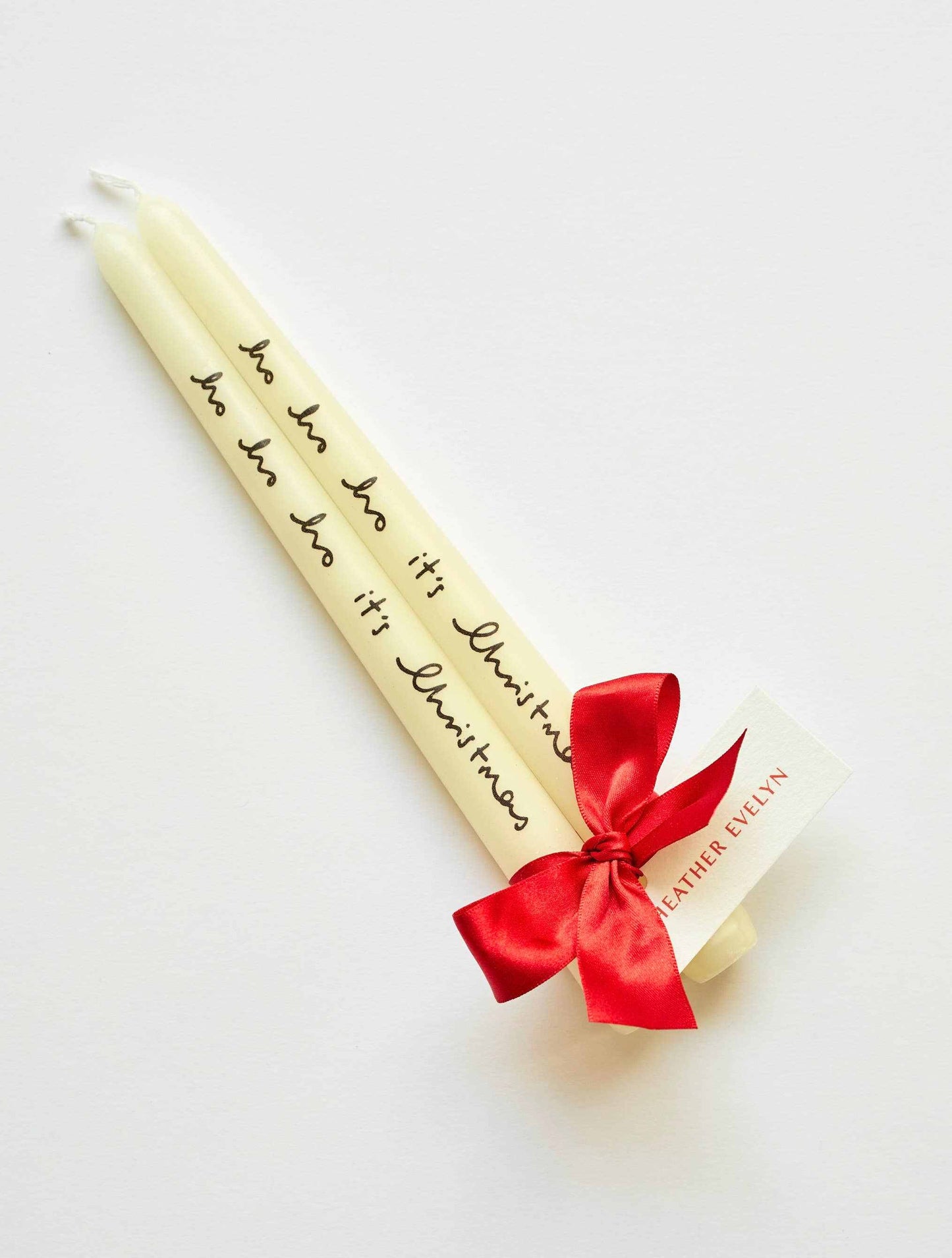 Pair of cream candles with "ho ho ho it's Christmas" text and red ribbon bow
