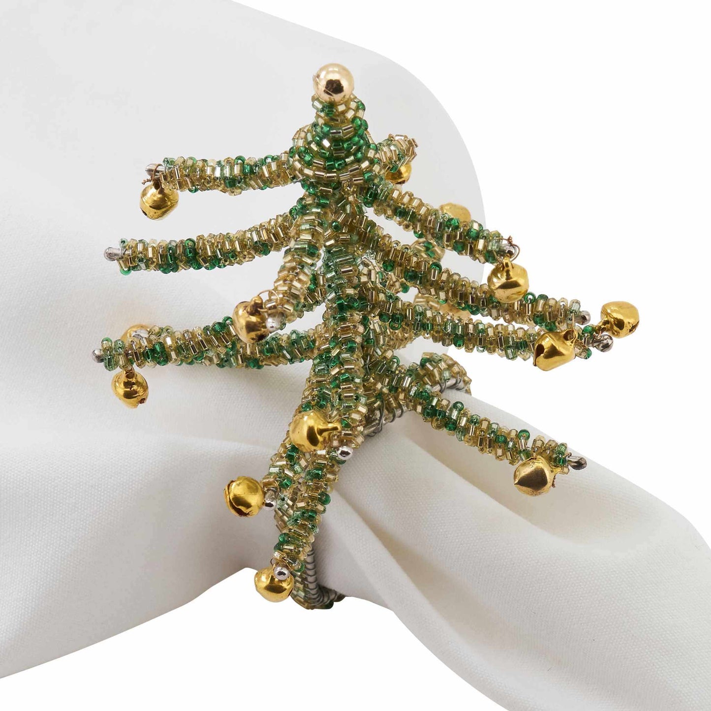 Green beaded Christmas tree napkin ring with gold jingle bell decorations on white napkin