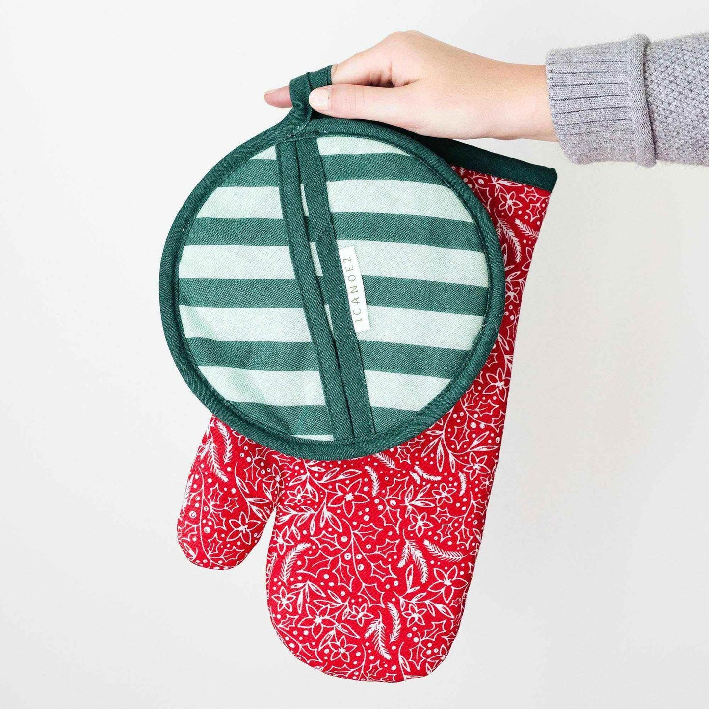 Holiday Floral Pot Holder Set with green striped pot holder and red floral oven mitt held in hand