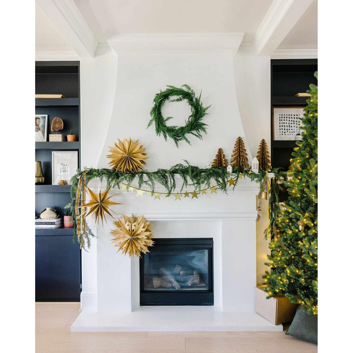 
                  
                    Christmas Memories medium 11-inch kraft paper accordion tree decor on fireplace mantel with garland and Christmas tree lights
                  
                
