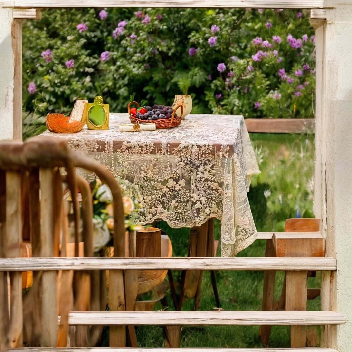 
                  
                    Vintage-style floral white lace tablecloth on outdoor wooden table with fruit baskets
                  
                