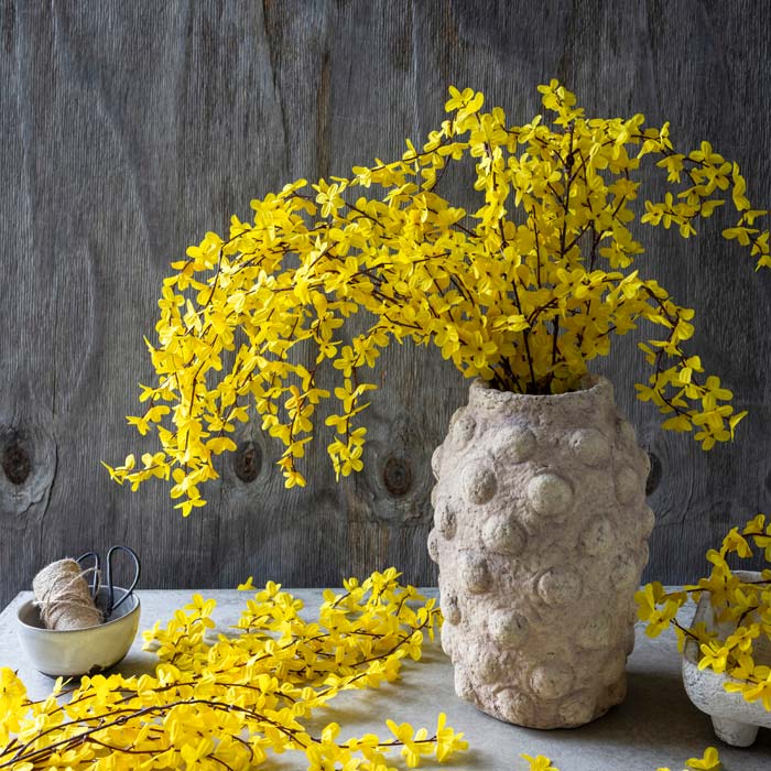
                  
                    Bouquet of Abigail Ahern artificial forsythia amber stems arranged in a textured vase
                  
                