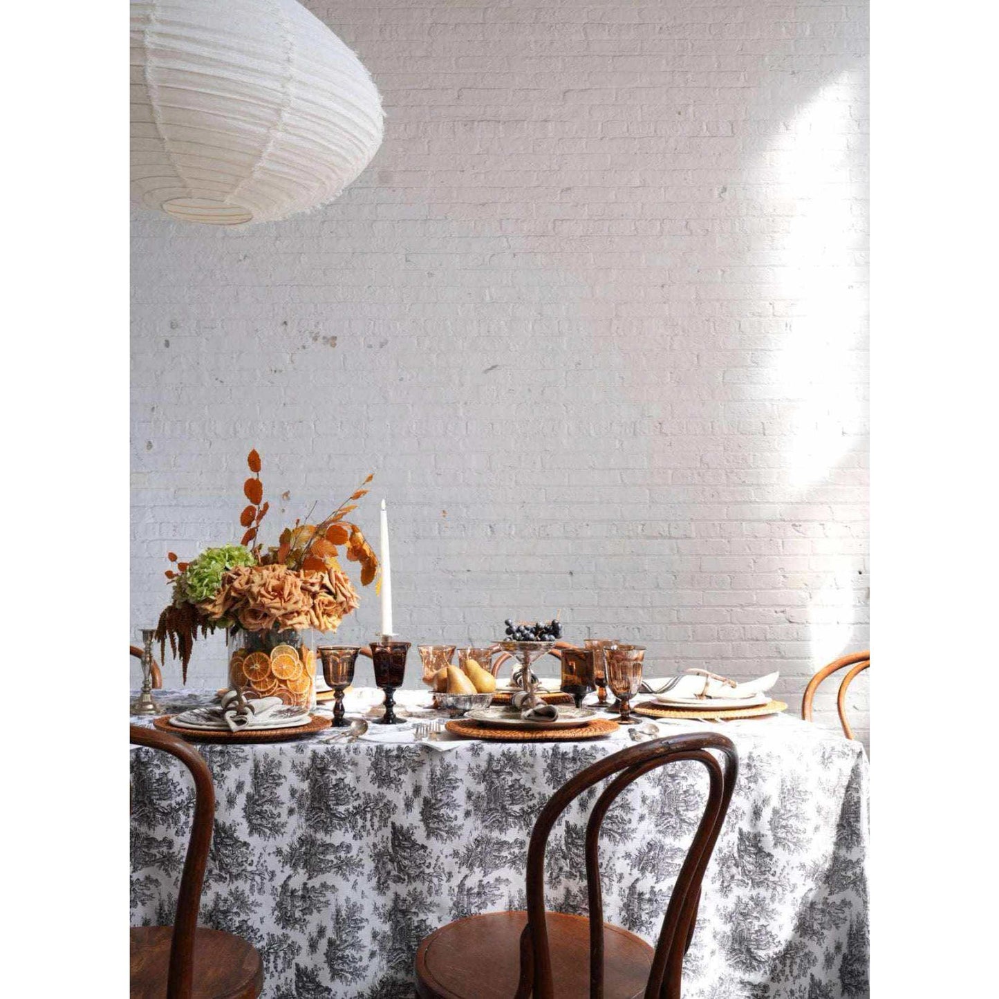 Oversized black and white botanical toile tablecloth on farmhouse dining table with rustic decor