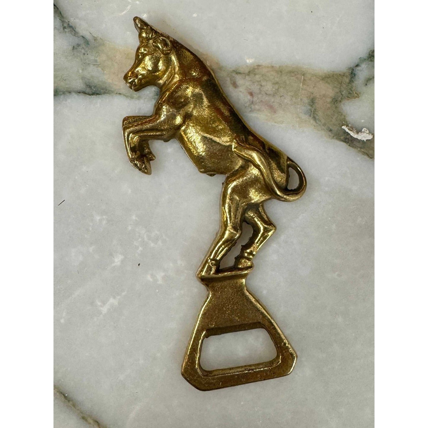 Vintage brass bull bottle opener with rearing stance and aged patina, functional and decorative bar accessory.