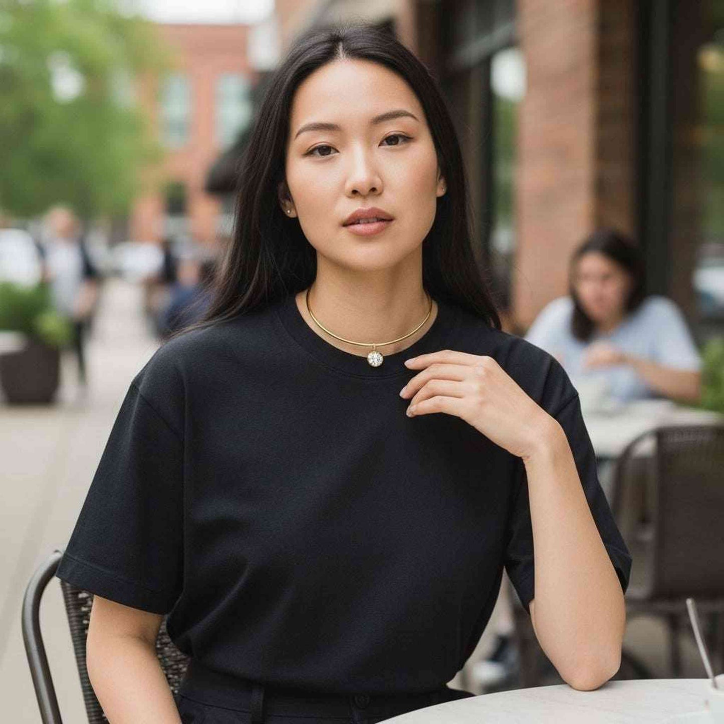 Woman wearing gold-plated collar necklace with round stone pendant and black top