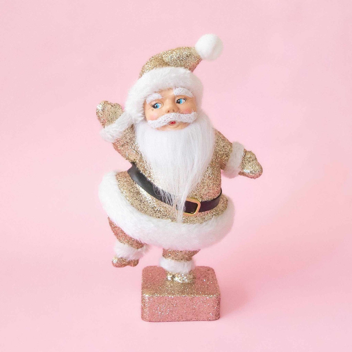 Retro Flocked Dancing Santa figurine in gold sparkle with fuzzy texture and playful dancing pose on pink background