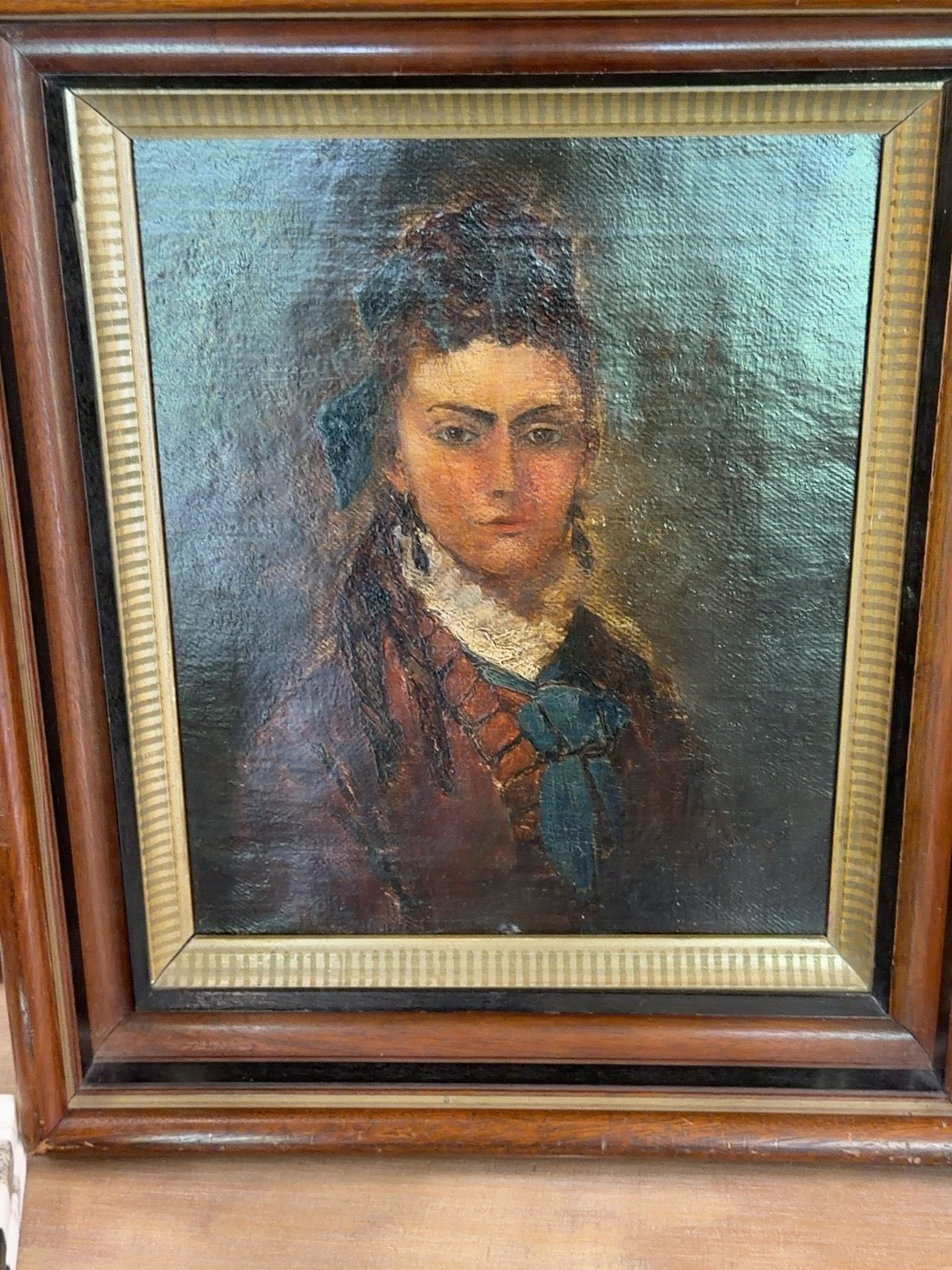 
                  
                    Close-up of antique oil portrait of a woman with blue bow
                  
                