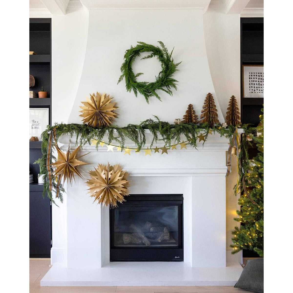 
                  
                    Christmas Memories medium 11-inch kraft paper accordion tree decor on festive white fireplace mantel with greenery and gold star garland
                  
                