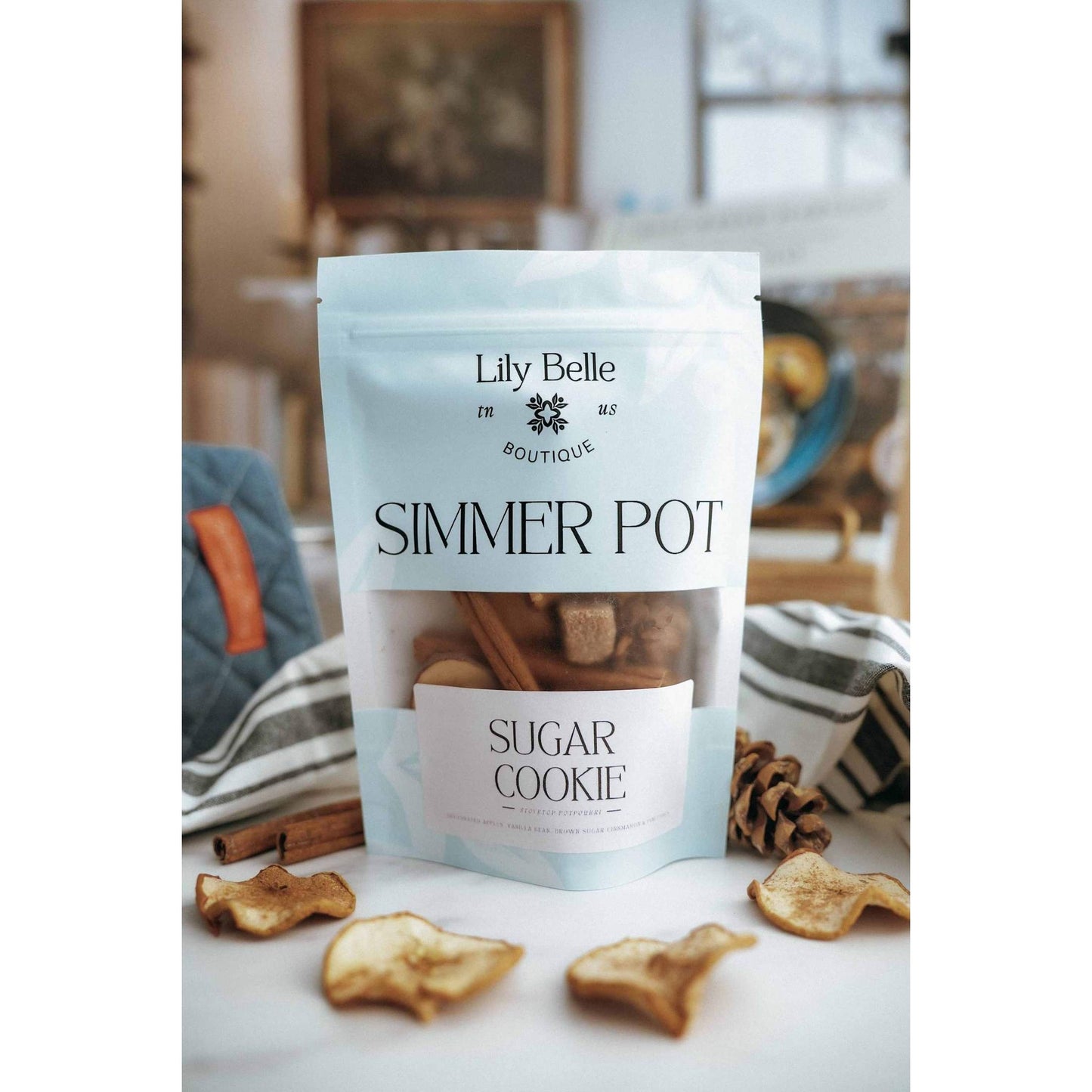 Sugar Cookie Simmer Pot with apple, vanilla, and cinnamon blend in resealable pouch surrounded by dried apple slices and cinnamon sticks