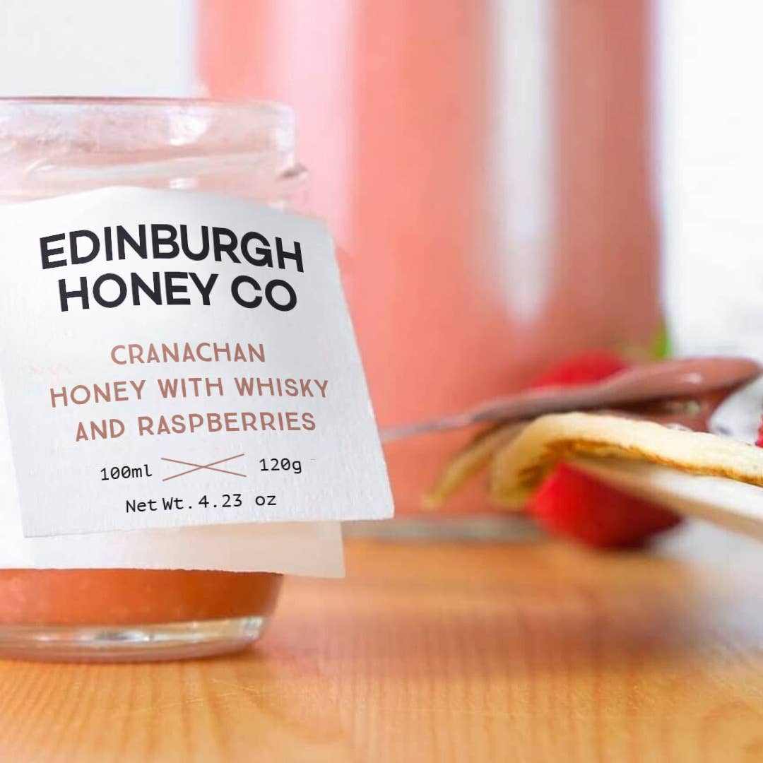 Jar of Cranachan honey with whisky and raspberries by Edinburgh Honey Co on wooden table with toast and knife