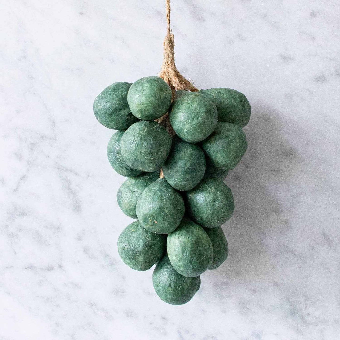 Handcrafted grape soap shaped like green olive oil grapes with hanging string on marble surface
