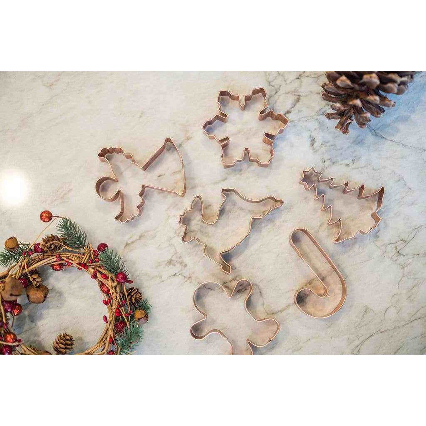 Set of 6 copper Christmas cookie cutters in festive shapes including tree, angel, reindeer, snowflake, candy cane, and gingerbread man.