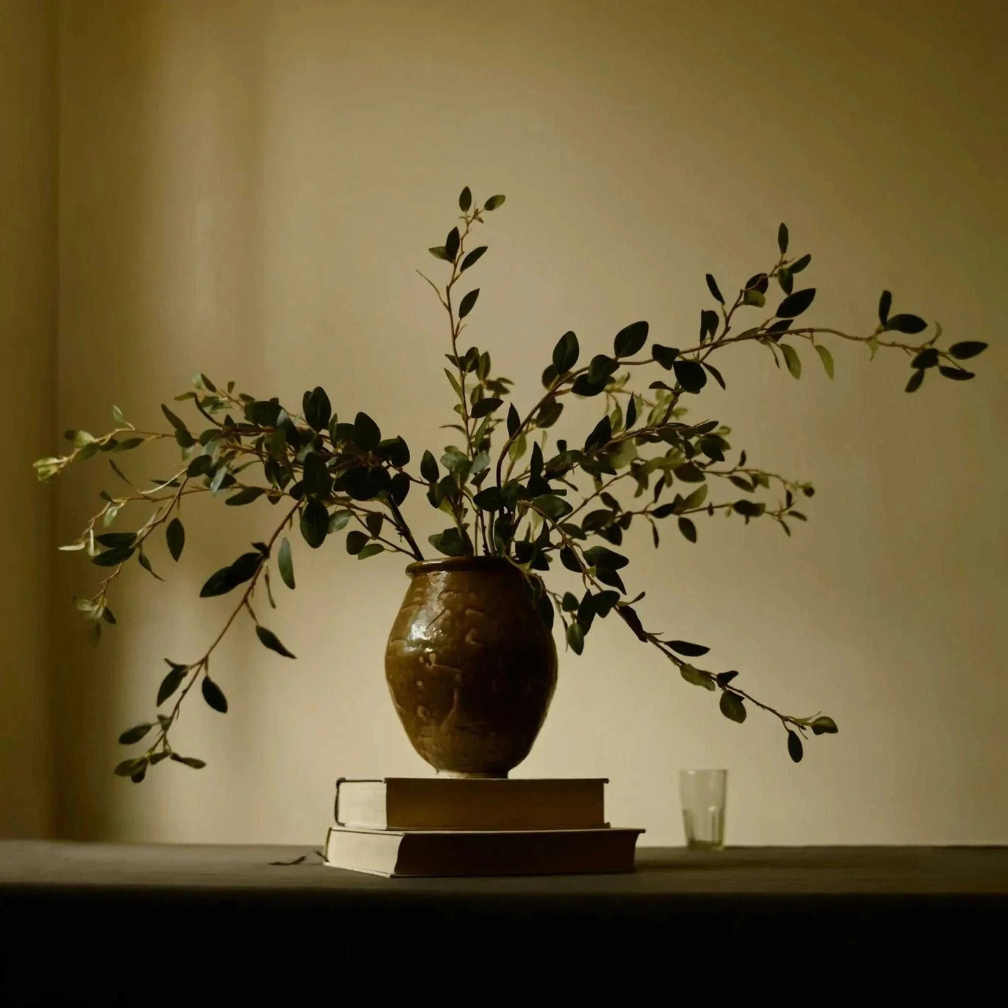 Creeping Willow Branch arrangement in vase on books with soft natural light background