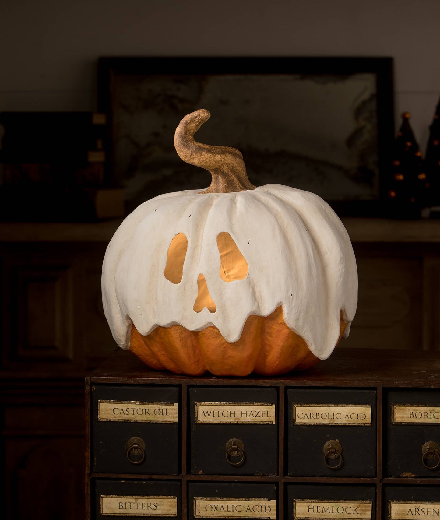 Ghost Jack Paper Mache jack o'lantern with white ghostly drapery and cut out eyes and nose on wooden cabinet