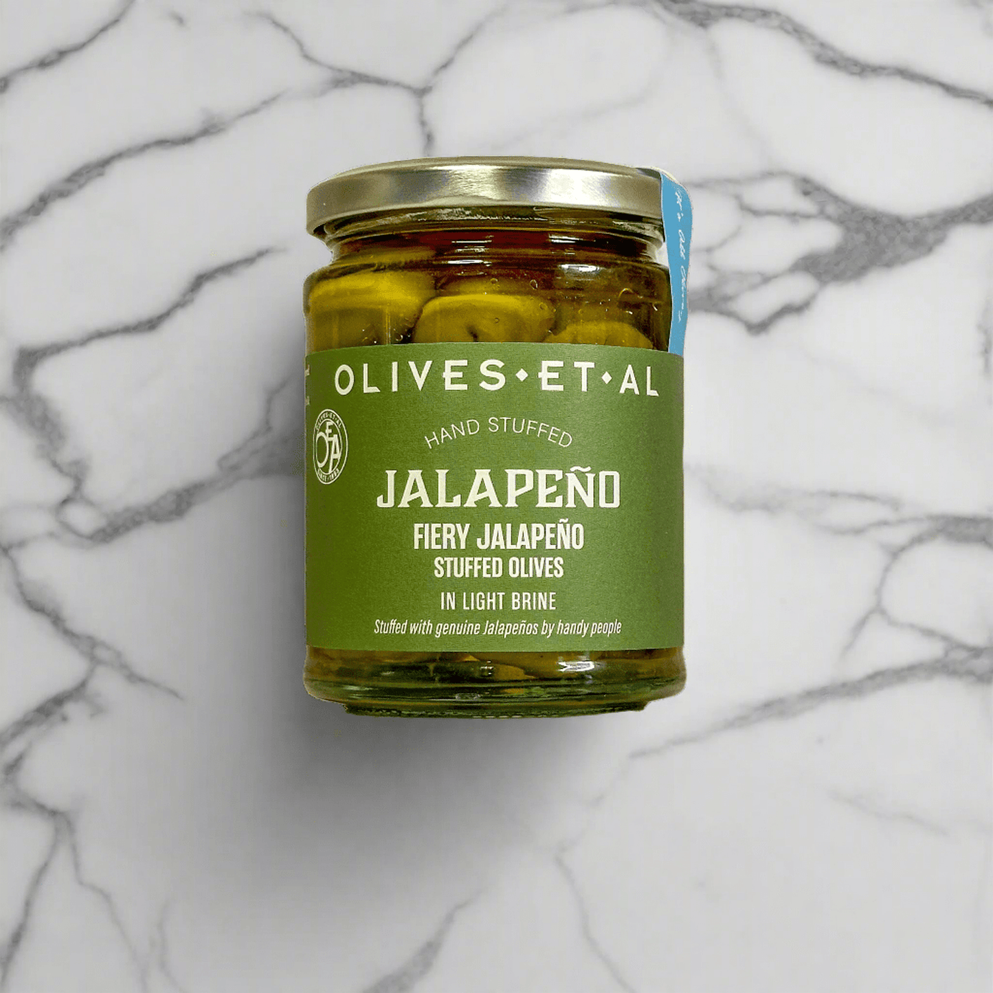Jar of Fiery Jalapeno Stuffed Olives in light brine on marble surface