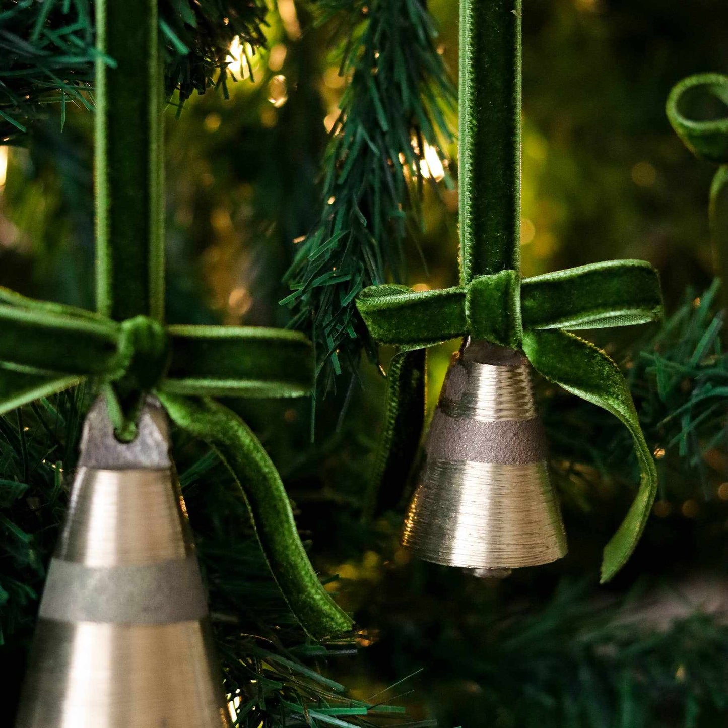 Christmas tree ornament bell with velvet ribbon hanging on tree branches