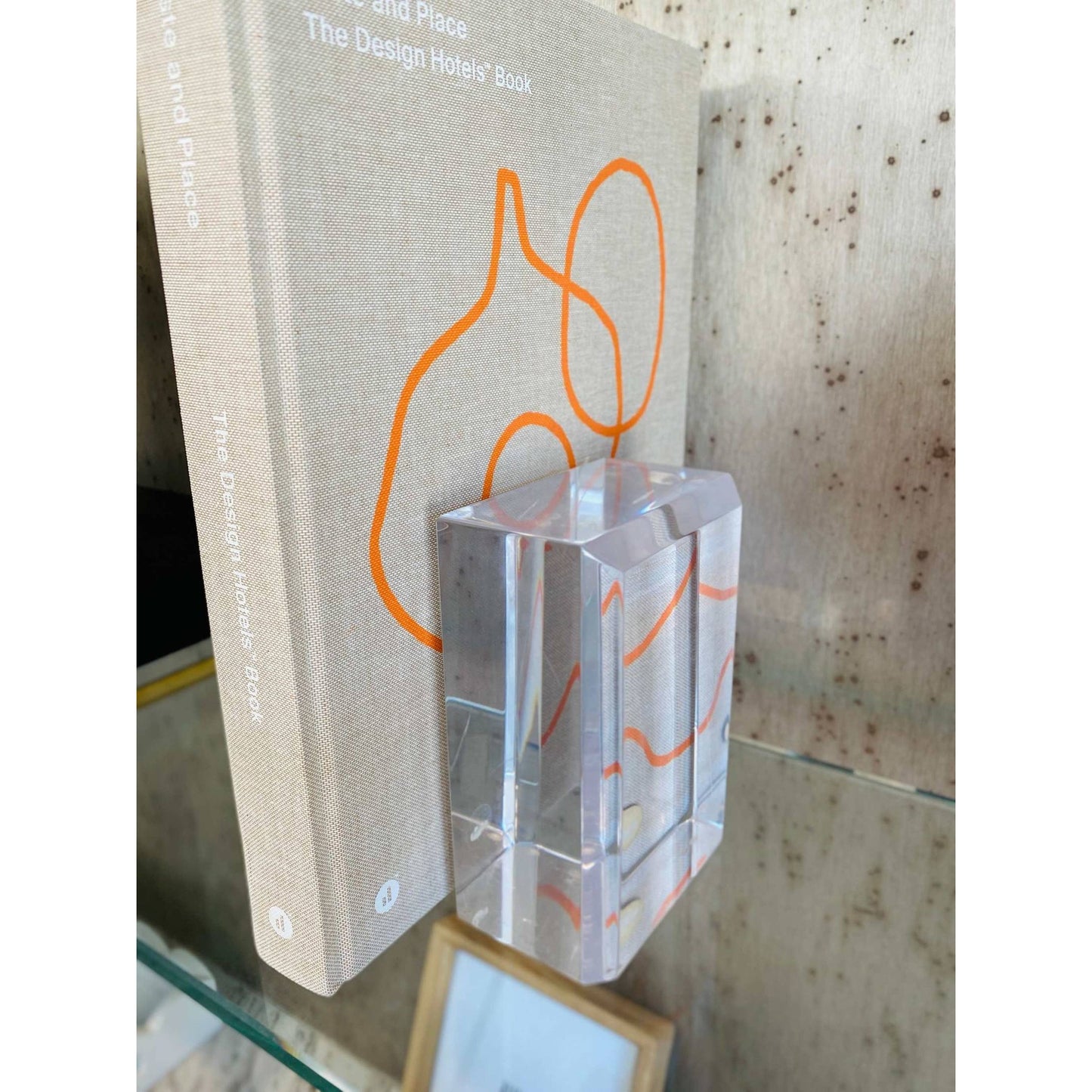
                  
                    Astrolite beveled faceted clear lucite bookends holding a book on a glass shelf
                  
                