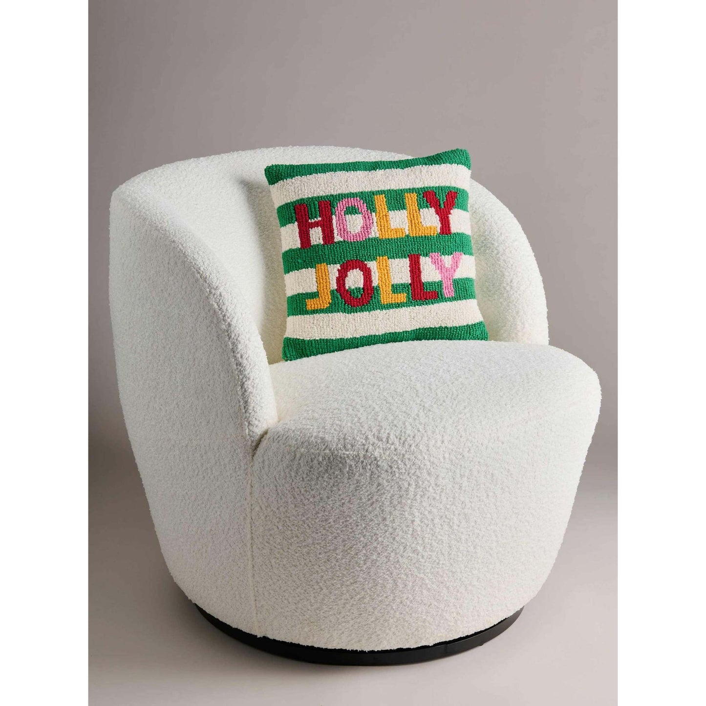 HOLLY JOLLY tufted holiday pillow with colorful lettering on striped background on white chair