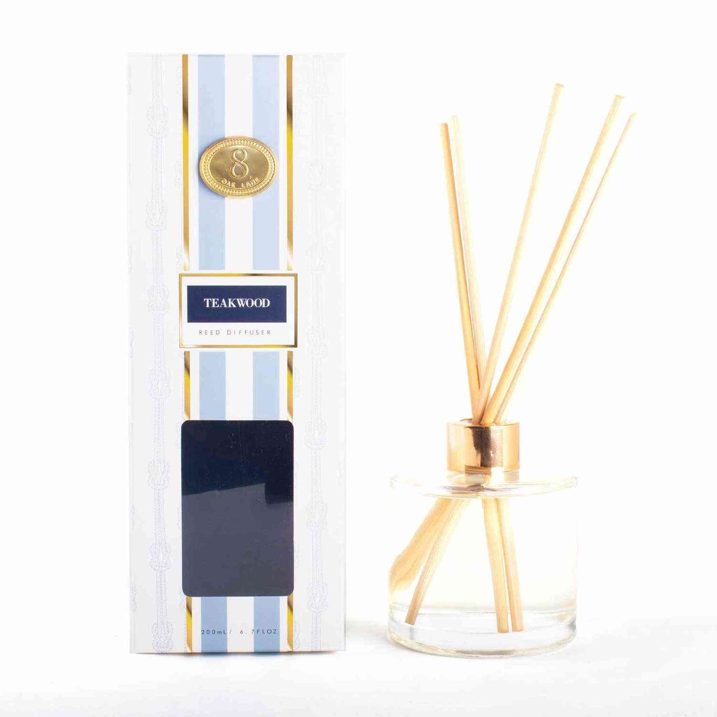 Teakwood reed diffuser with amber, sandalwood, cardamom, and lily of the valley scent in glass bottle and striped nautical packaging
