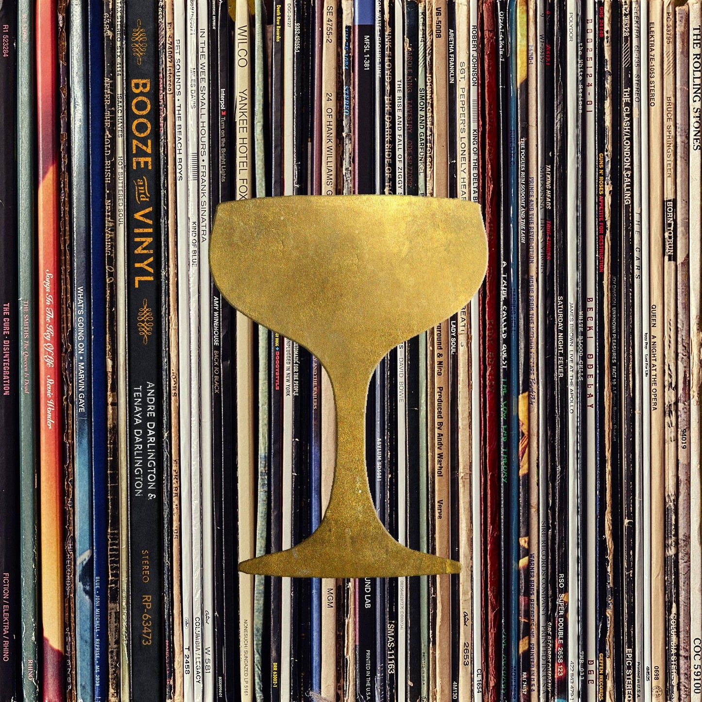 Booze & Vinyl book among vinyl records with gold cocktail glass icon on cover