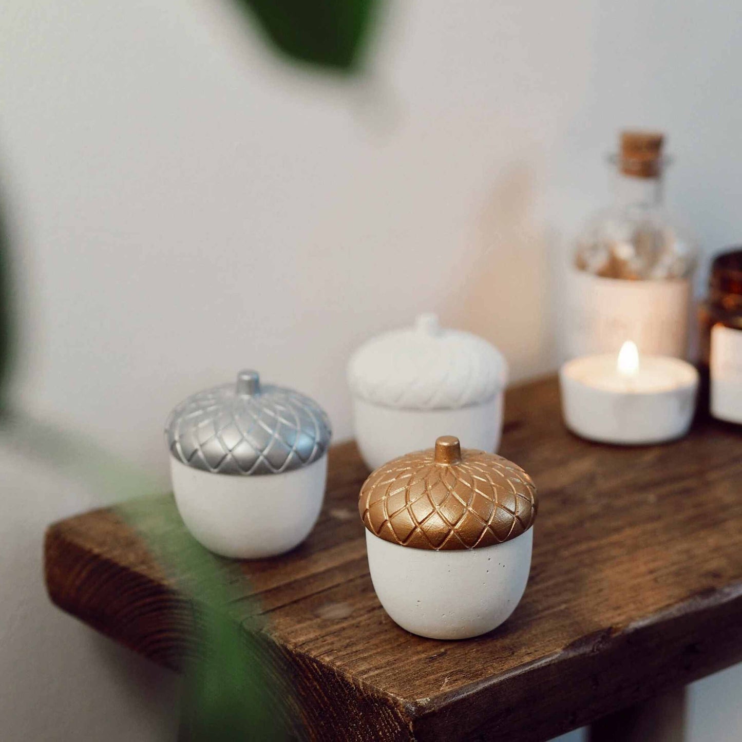 Handmade solid white concrete acorn paperweight with gold top on wooden surface for autumn decor