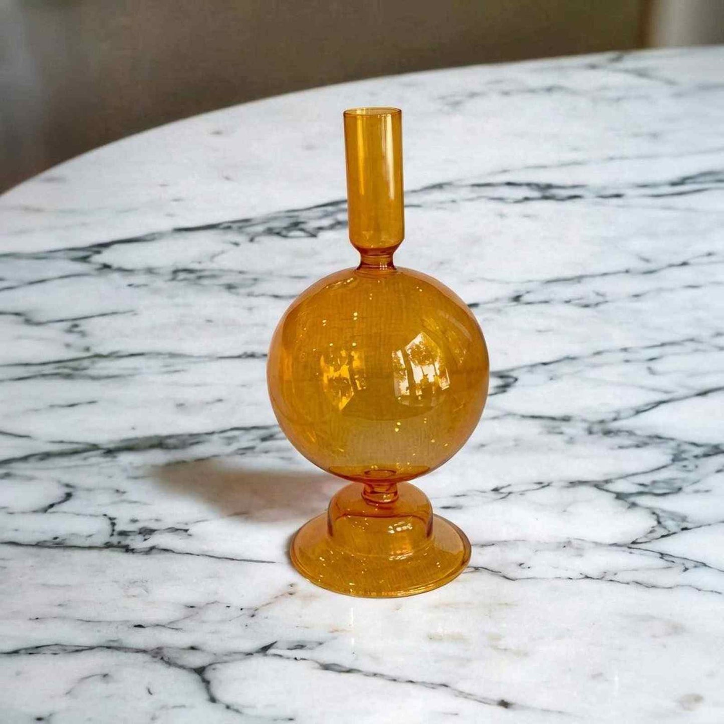 Orange round glass candlestick holder with warm glow and elegant design
