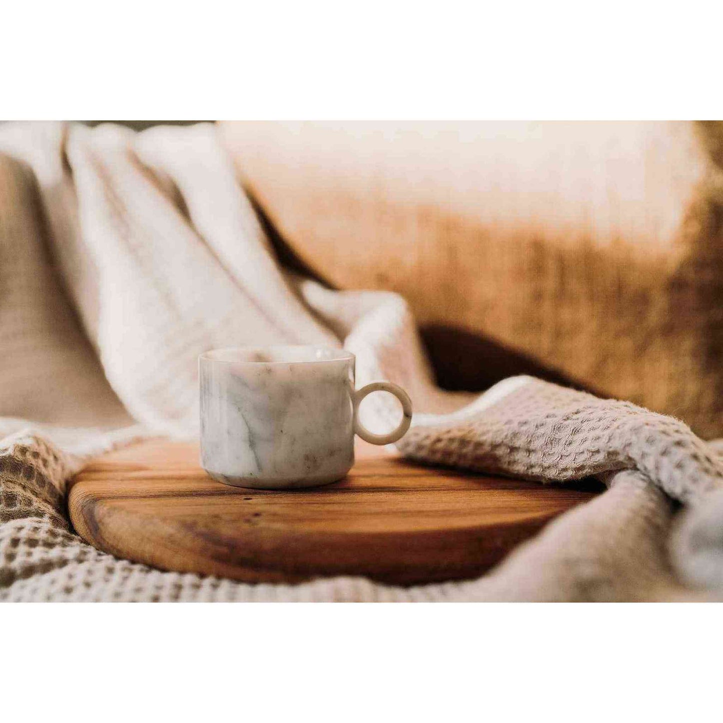 white marble tea cup made from Italian carrara marble on wooden board with cozy knit blankets background