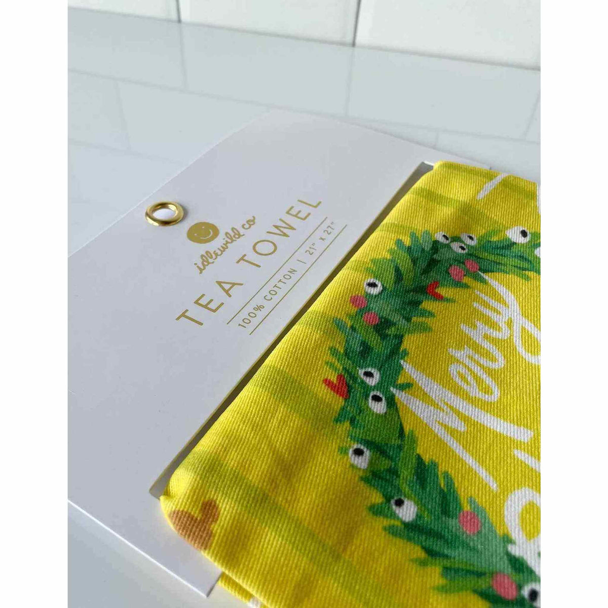 
                  
                    Festive fireplace tea towel with vibrant colors and embroidered trim hanging in kitchen
                  
                