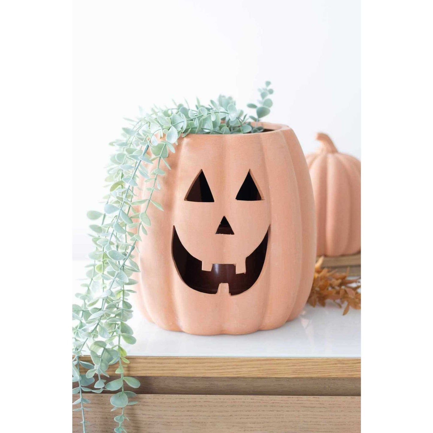 Terracotta cut out Halloween pumpkin decoration with jack-o'-lantern face and greenery inside