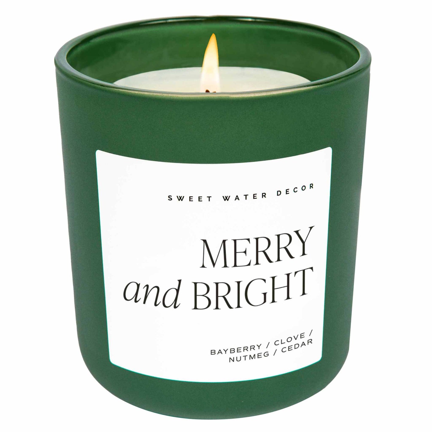 Merry and Bright 15 oz soy candle in matte green jar with festive bayberry, clove, nutmeg, and cedar scent burning