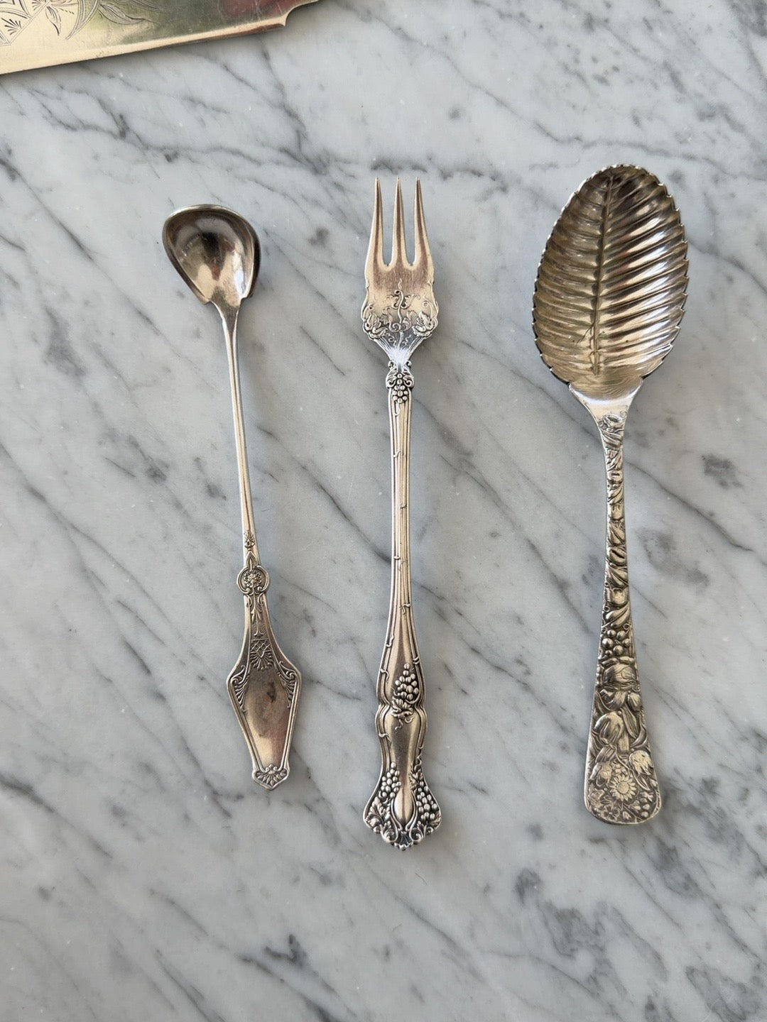 
                  
                    Vintage floral silverplate leaf-form serving spoon shown with collected serving utensils
                  
                