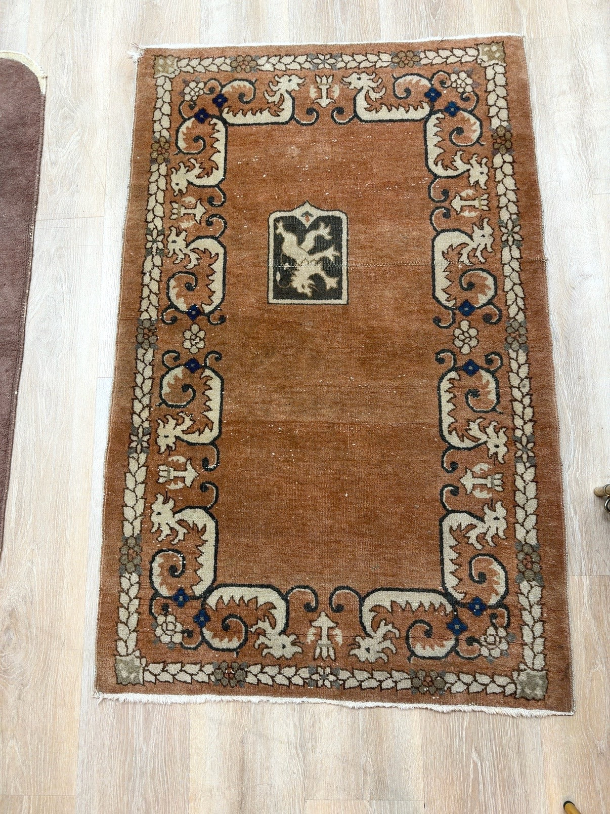 
                  
                    Full overhead view of vintage Turkish accent rug with terracotta field and heraldic crest
                  
                